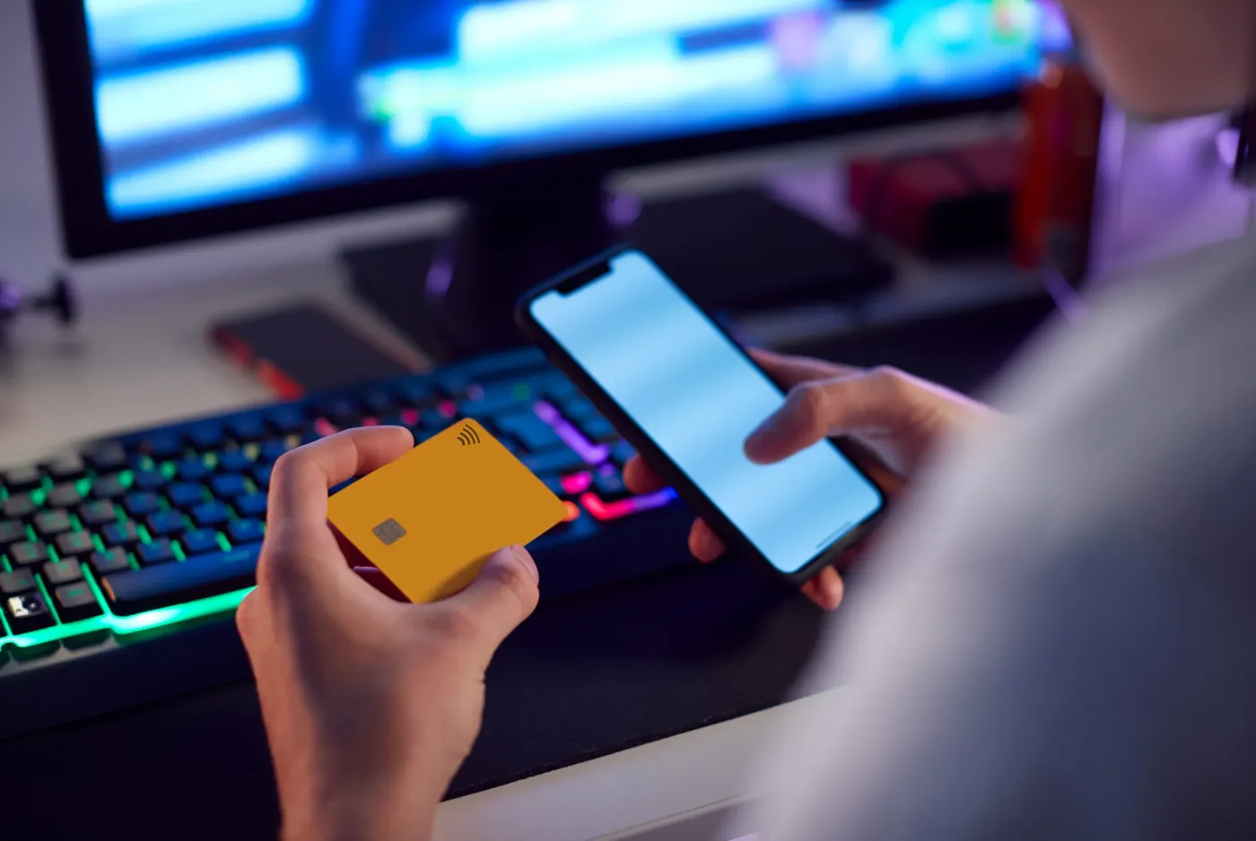 A person holding a payment card while browsing on a phone late at night
